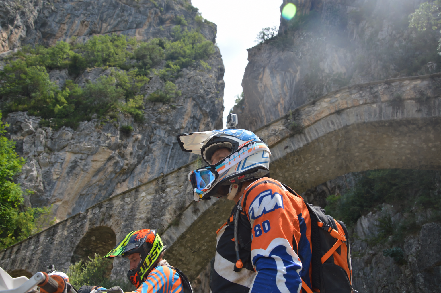 Enduro riders preparing beneath the stone bridge in Grevena