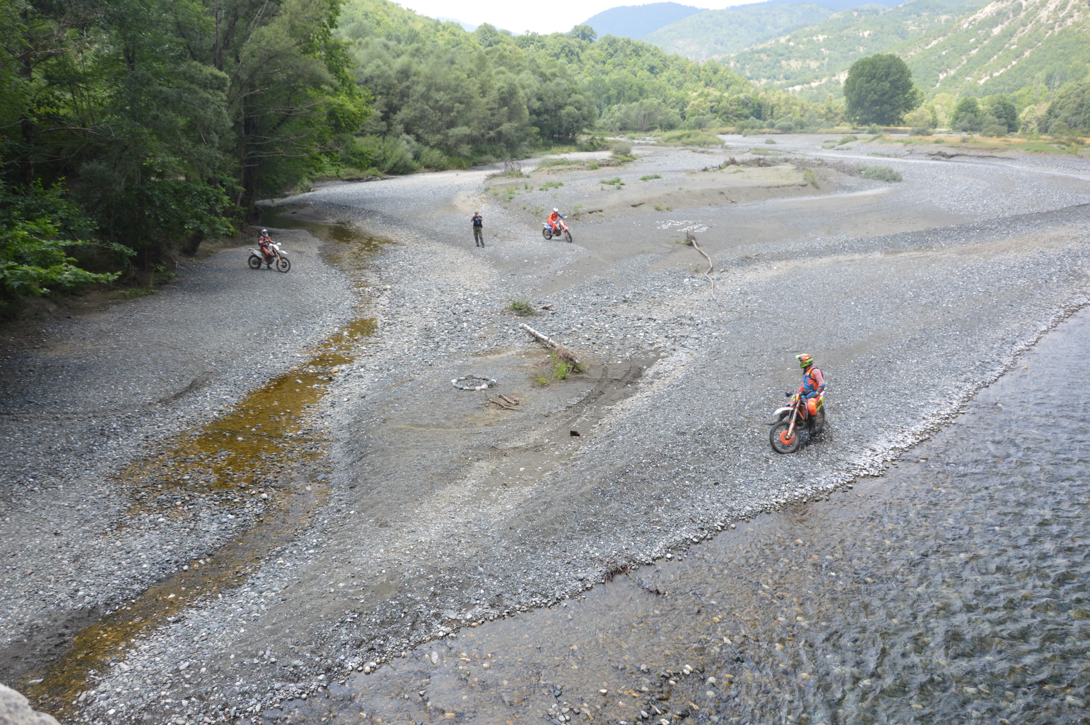 Enduro riders crossing the wide riverbed in the Grevena mountains