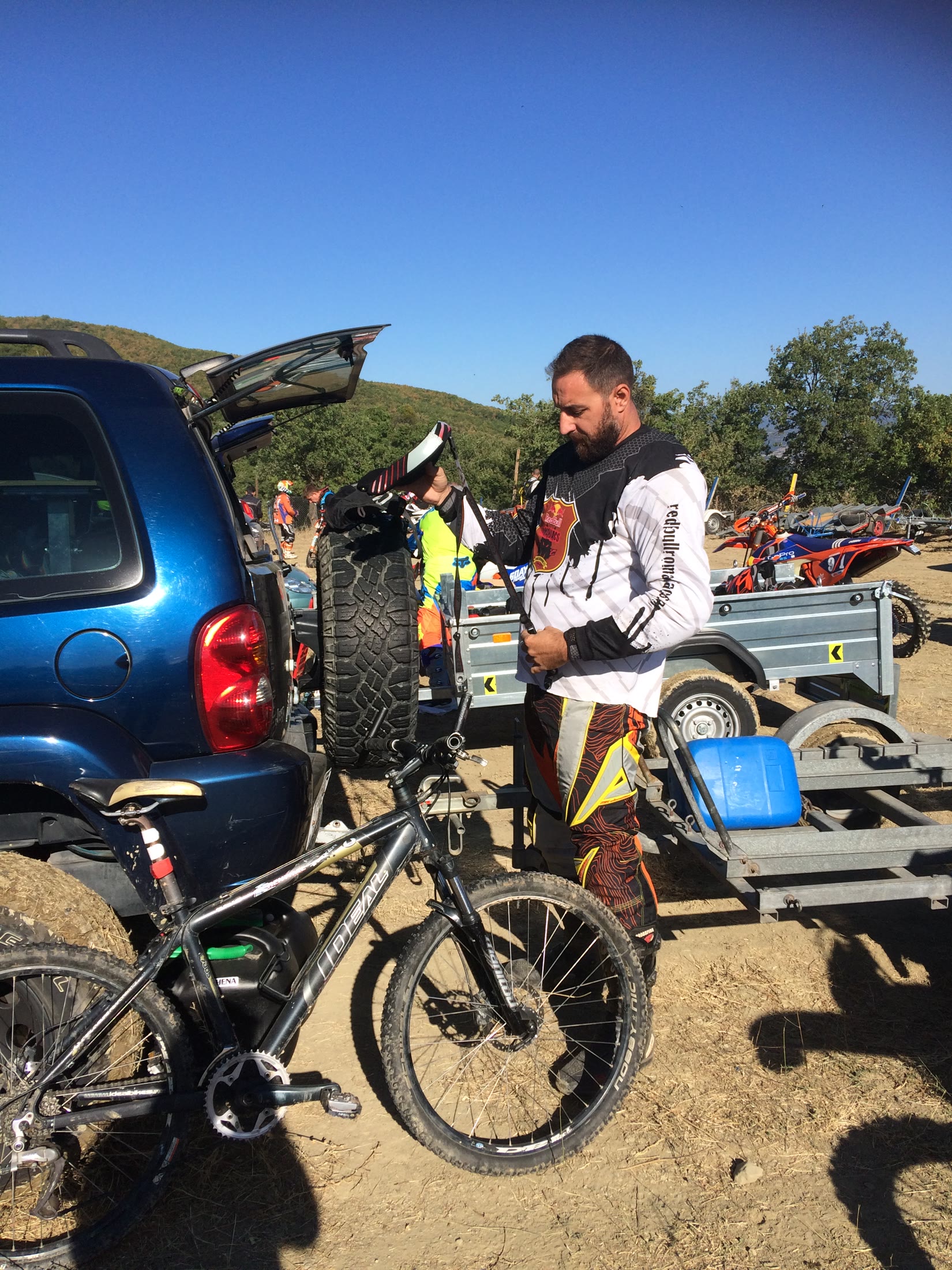 Rider preparing equipment beside motorcycles at the mountain race base