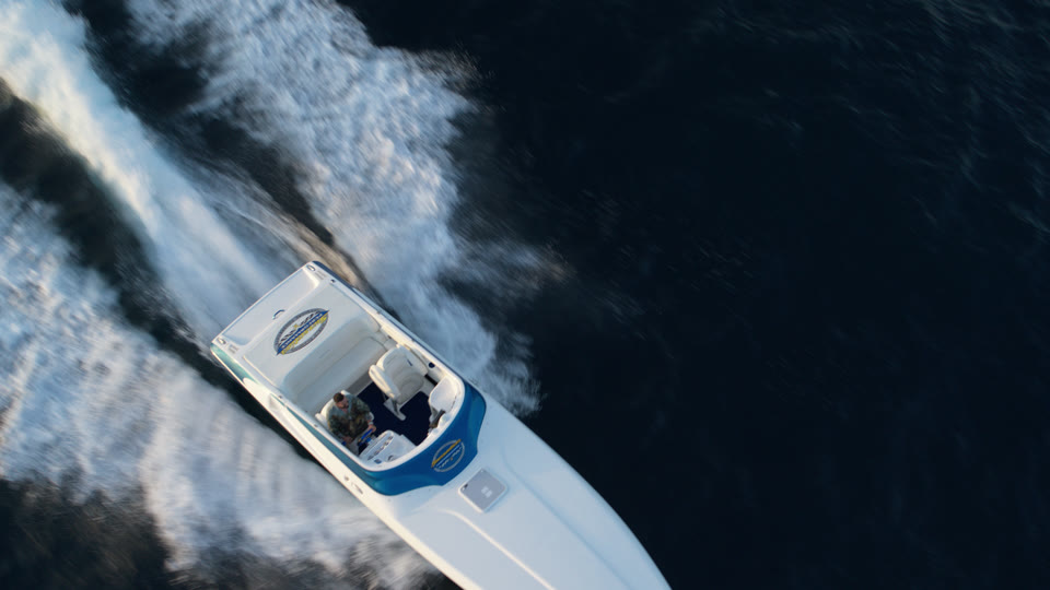 Top-down drone shot of a speedboat carving through water